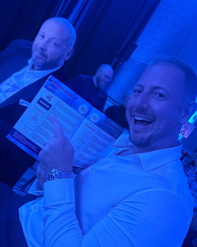 Photo of Jon Kennett pointing at the program during the meal at Brighton and Hove Business Awards 2026